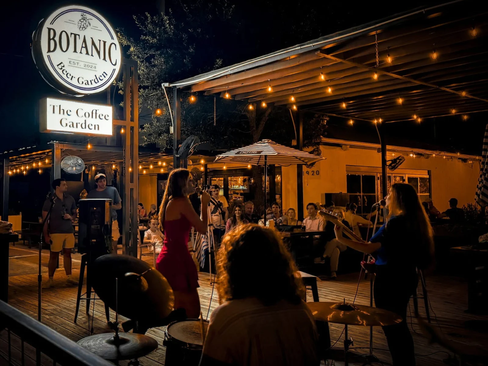 Outdoor patio at Botanic Beer Garden in Houston Heights with greenery, tables, string lights, and guests enjoying drinks