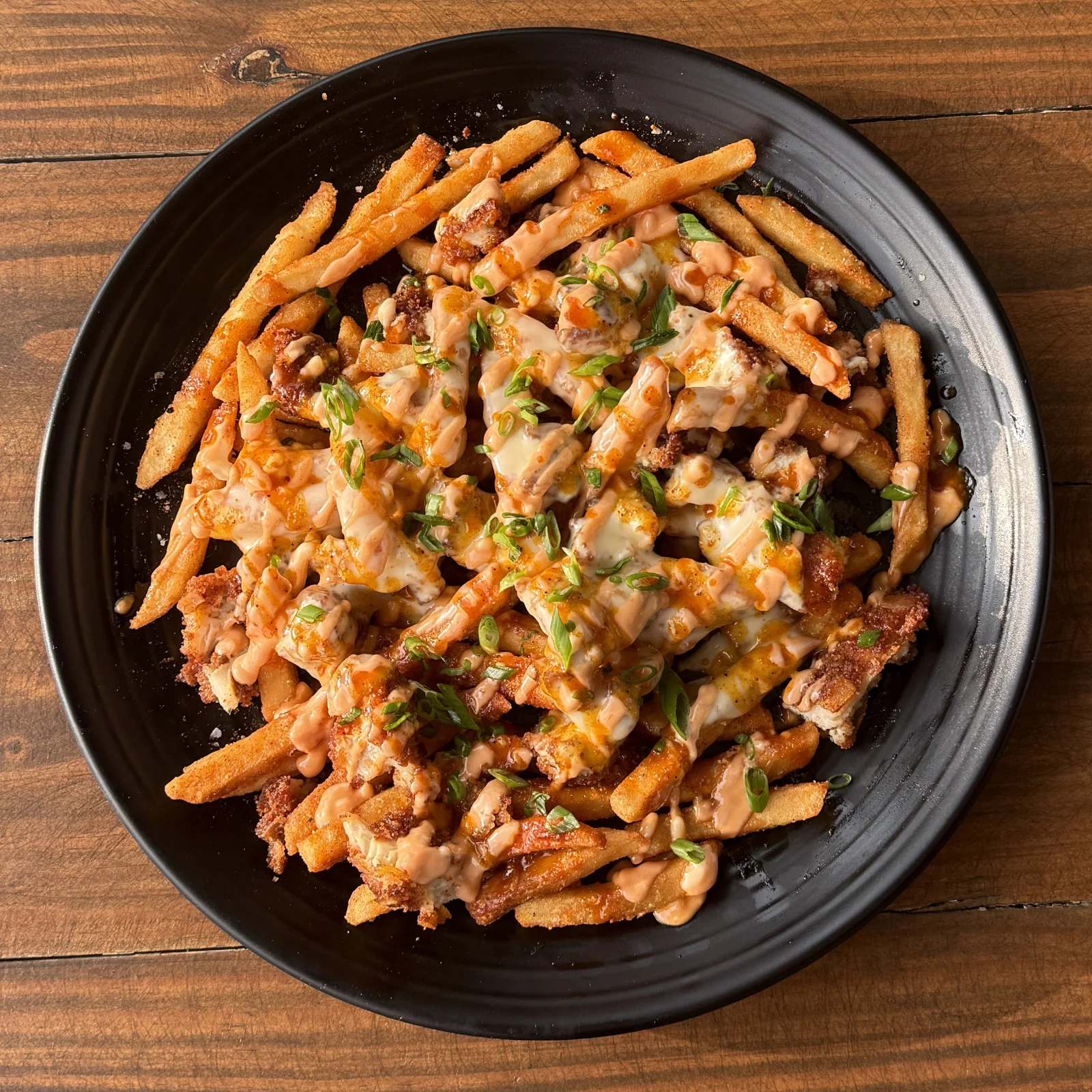 Loaded fries in the Heights topped with smoky sauce, green onions, and bacon bits at Botanic Beer Garden