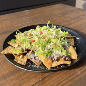 Steak nachos in the Heights with tortilla chips, black beans, cotija cheese, lettuce, and pico de gallo at Botanic Beer Garden