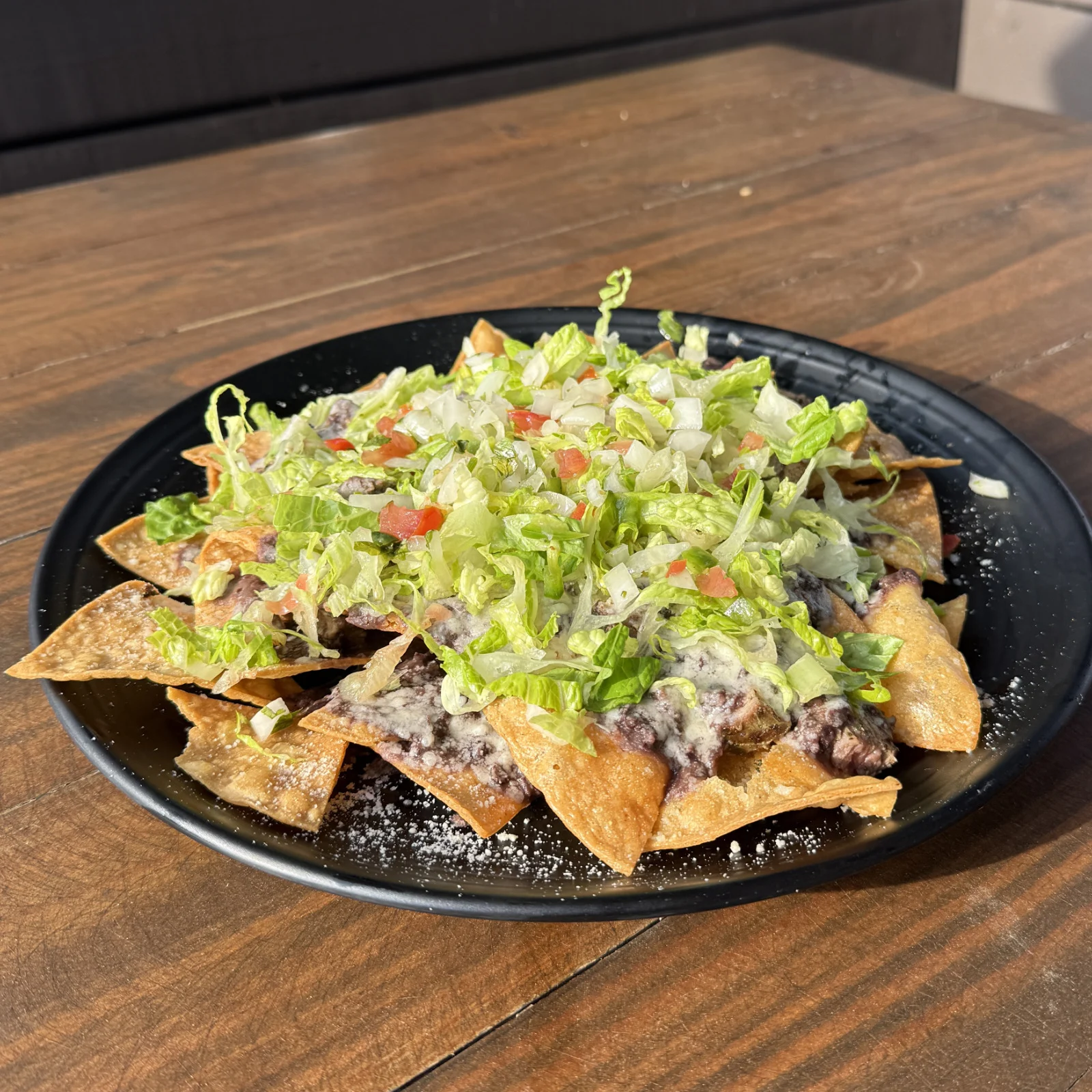 Steak nachos in the Heights with tortilla chips, black beans, cotija cheese, lettuce, and pico de gallo at Botanic Beer Garden