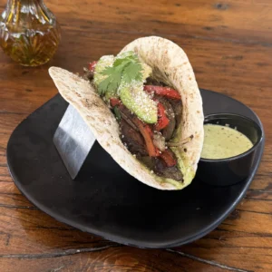 Steak taco in the Heights with grilled peppers, onions, cotija, and cilantro-lime sauce at Botanic Beer Garden
